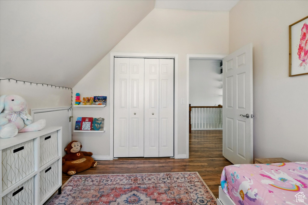 Bedroom with vaulted ceiling, wood finished floors, and a closet