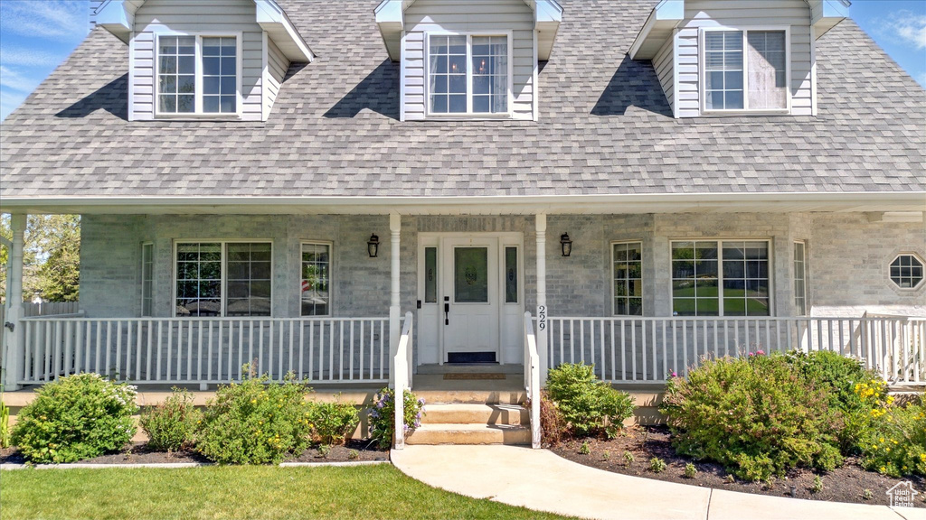 New england style home with covered porch and a shingled roof