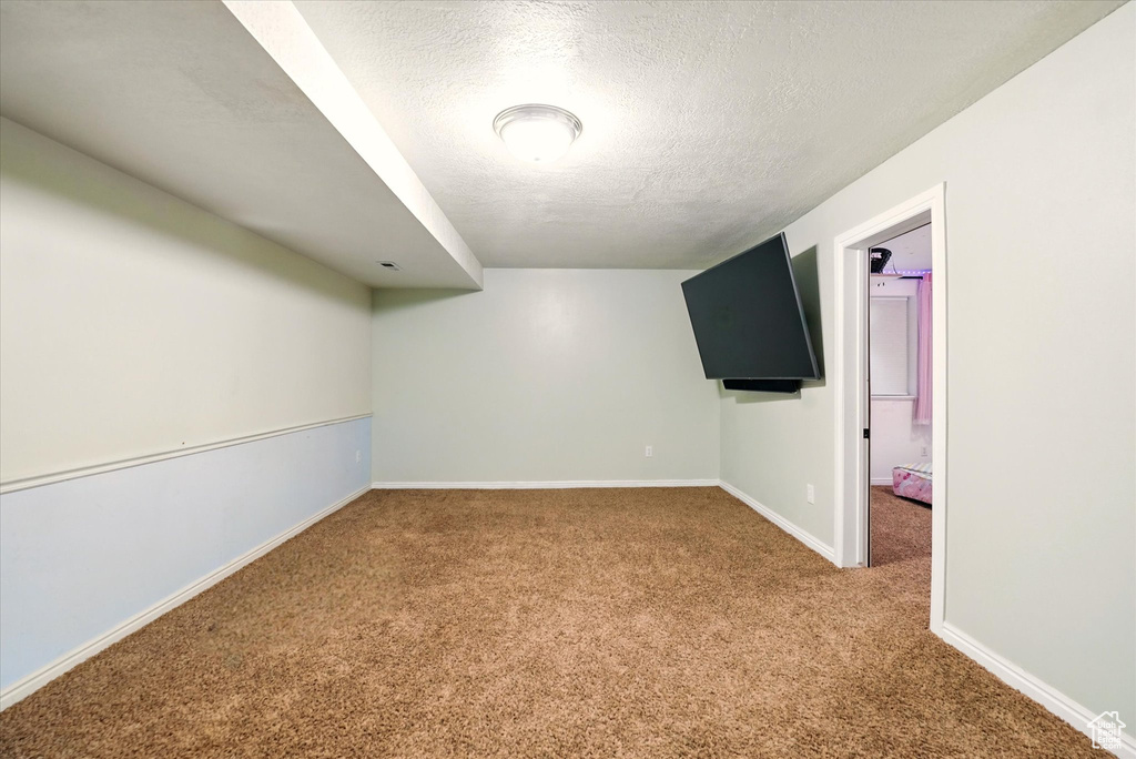 Carpeted spare room featuring a textured ceiling and baseboards