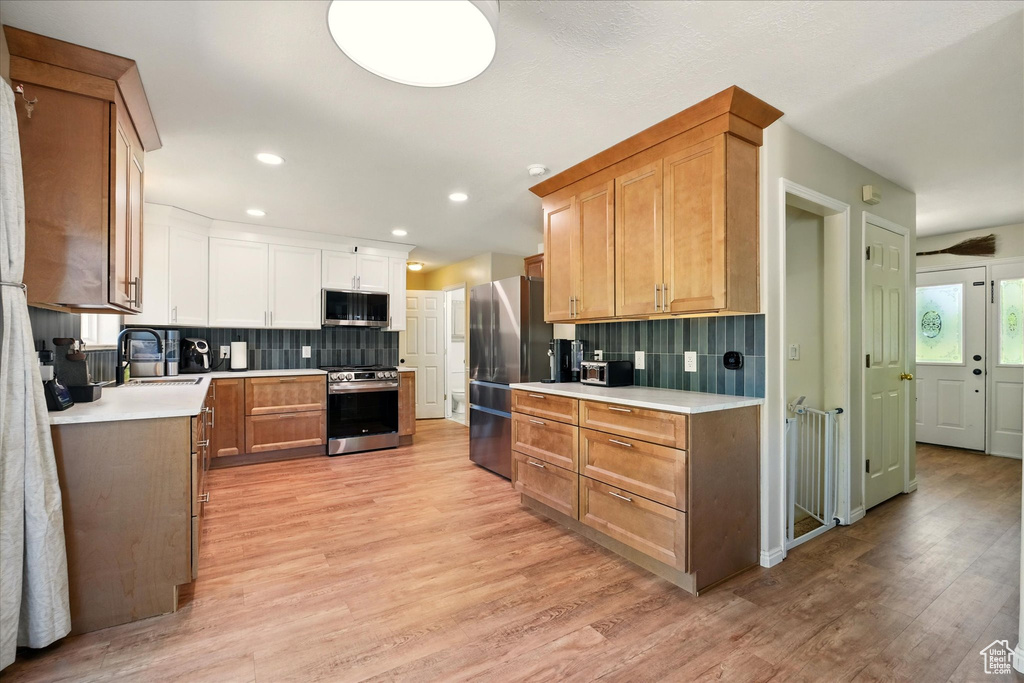 Kitchen featuring stainless steel appliances, light countertops, a sink, light wood-style flooring, and recessed lighting