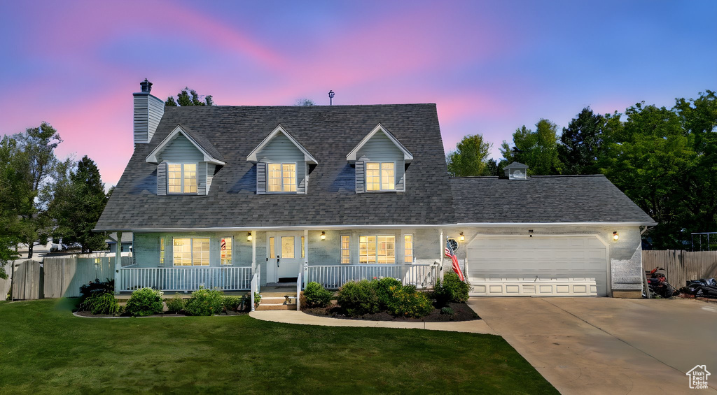Cape cod home featuring a chimney, a garage, driveway, covered porch, and a shingled roof