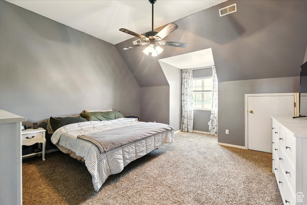 Bedroom featuring vaulted ceiling, light carpet, baseboards, and a ceiling fan