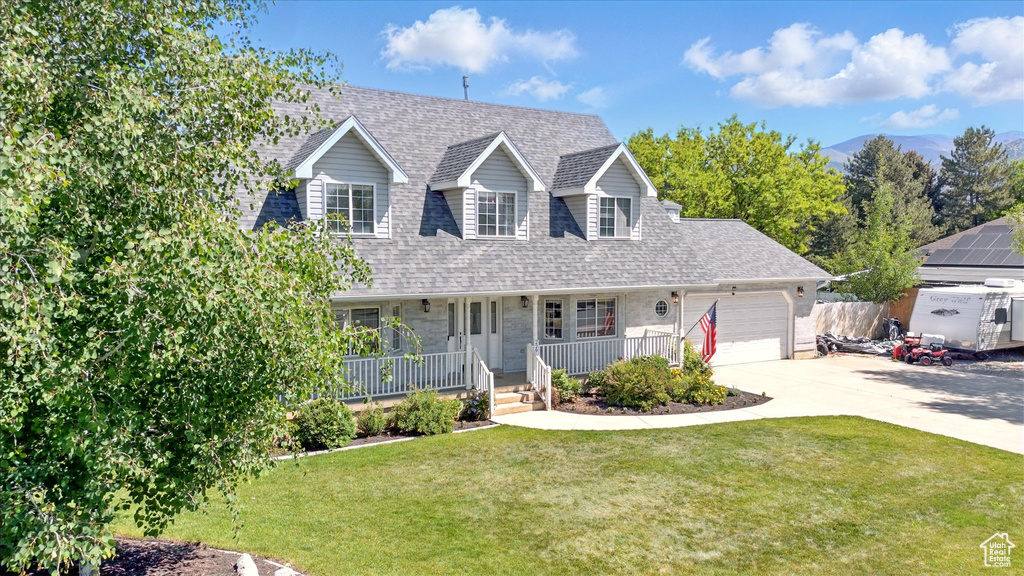 Cape cod home with covered porch, a garage, driveway, a front yard, and roof with shingles