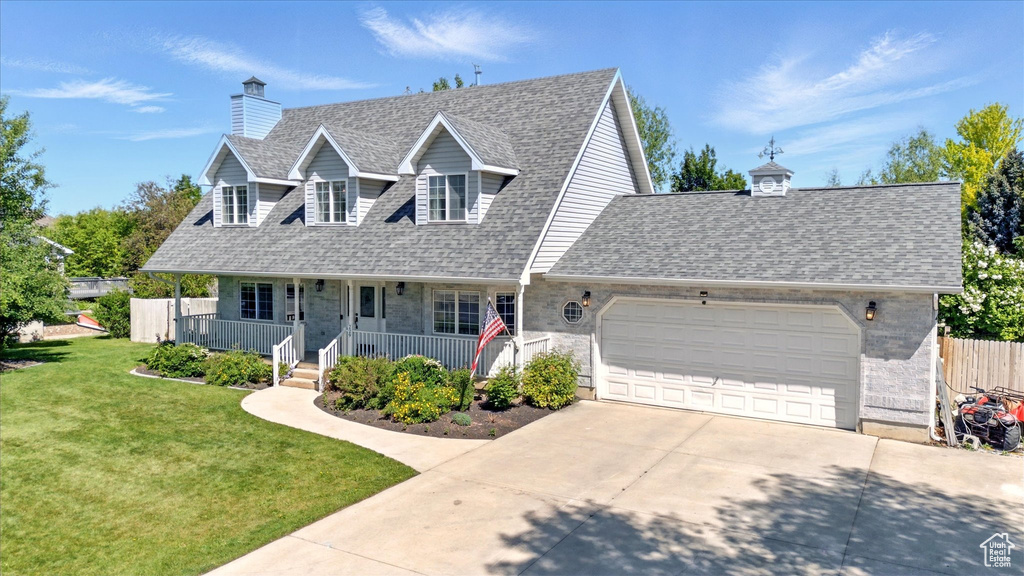 Cape cod home with concrete driveway, a shingled roof, an attached garage, and covered porch