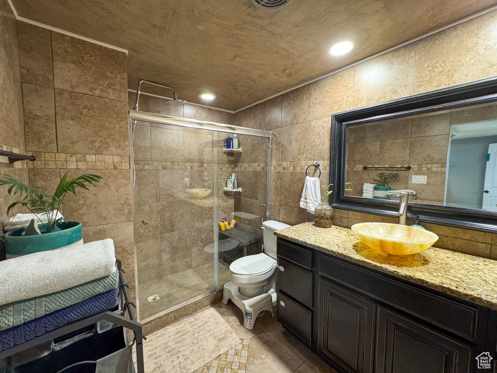 Full bath featuring tile walls, vanity, a shower stall, toilet, and recessed lighting