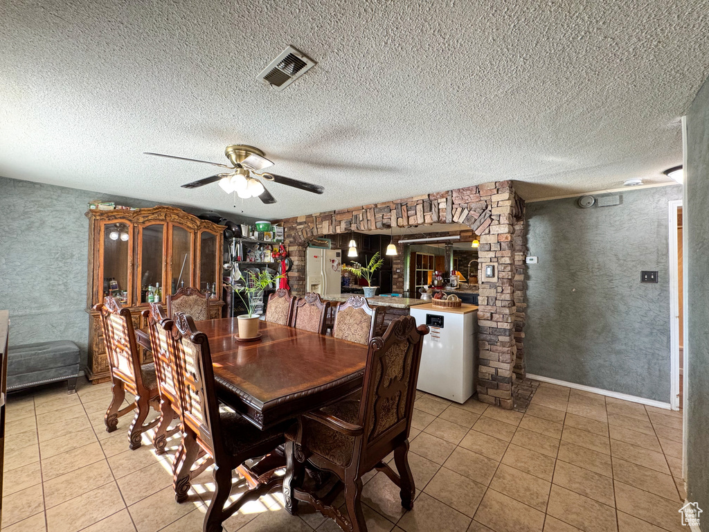 Dining room with light tile patterned flooring, ceiling fan, and a textured ceiling