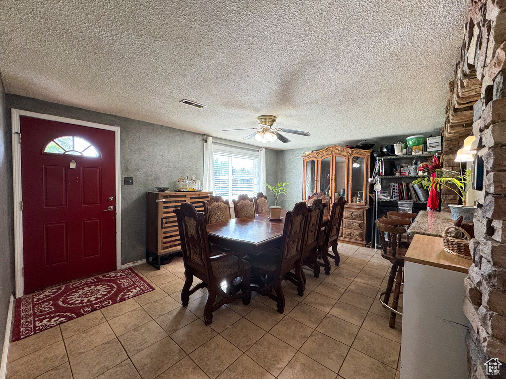 Dining room with a ceiling fan, light tile patterned flooring, and a textured ceiling