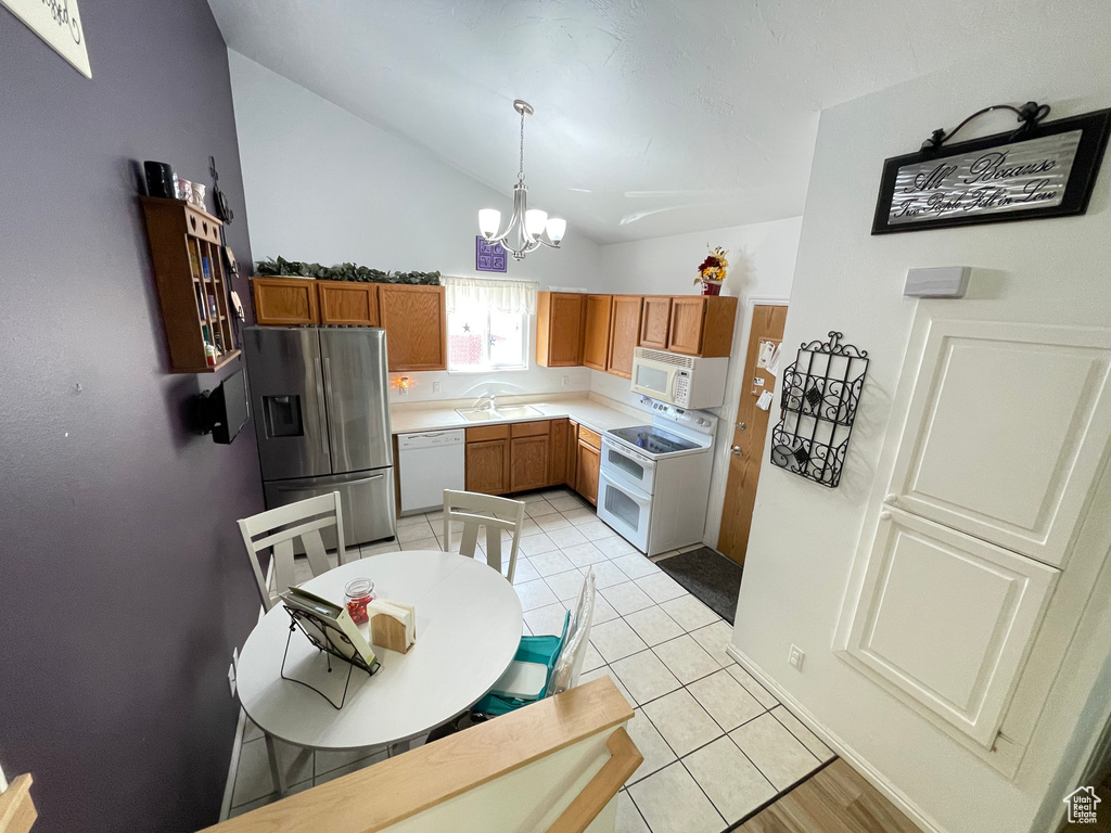 Kitchen with white appliances, lofted ceiling, a chandelier, light countertops, and decorative light fixtures