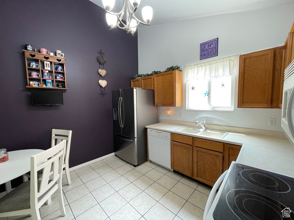 Kitchen featuring white dishwasher, stainless steel fridge, a chandelier, brown cabinets, and electric stove