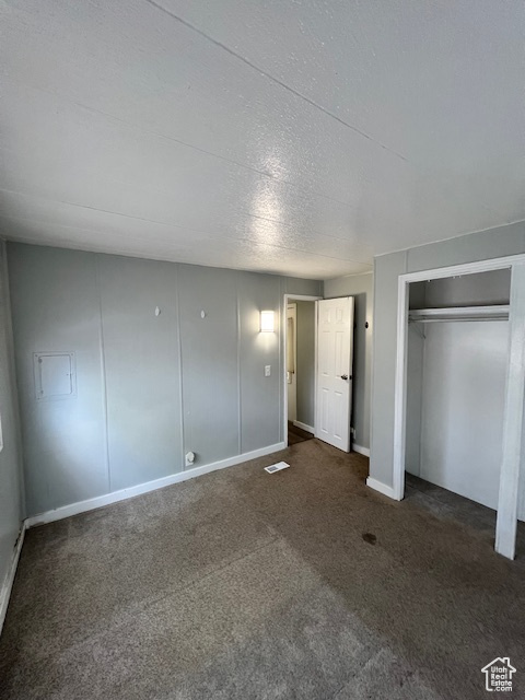 Unfurnished bedroom featuring carpet, a textured ceiling, and baseboards