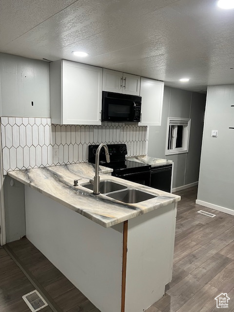 Kitchen with black appliances, a sink, white cabinetry, a textured ceiling, and tasteful backsplash