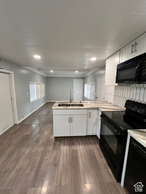 Kitchen featuring black appliances, a sink, a peninsula, white cabinets, and dark wood finished floors