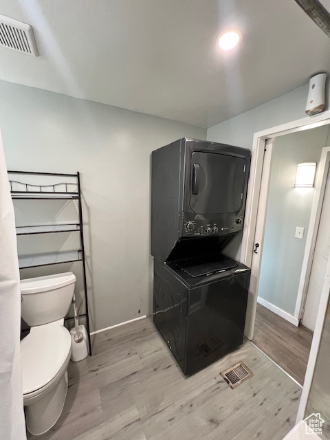 Kitchen with estacked washer and dryer, wood finished floors, and baseboards