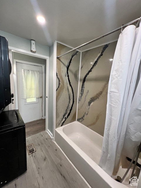 Bathroom featuring wood finished floors, shower / bath combo with shower curtain, and vanity