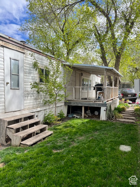 Rear view of house with a lawn, entry steps, and a wooden deck