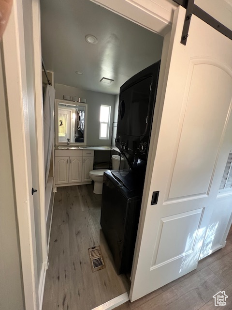 Laundry room featuring stacked washer / dryer and wood finished floors