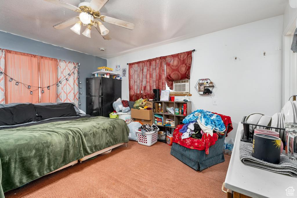Carpeted bedroom featuring freestanding refrigerator and ceiling fan