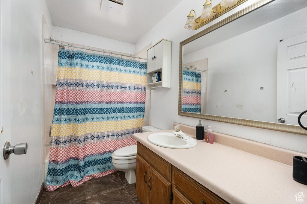 Full bath with toilet, vanity, and curtained shower