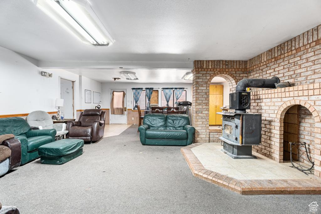 Living room with a wood stove, carpet flooring, and brick wall