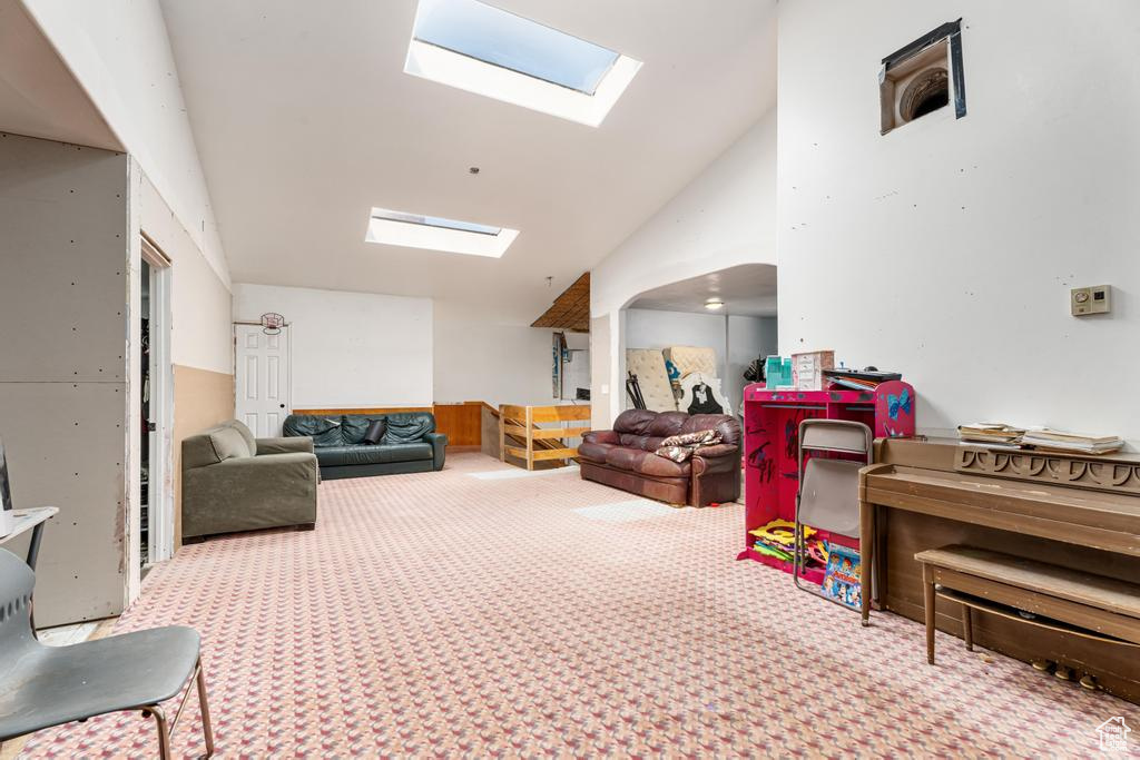 Interior space with a skylight, carpet, and lofted ceiling