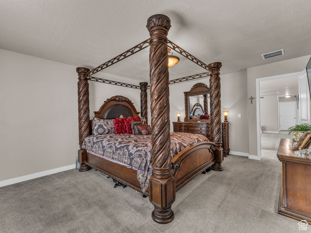 Bedroom featuring light colored carpet, baseboards, and a textured ceiling