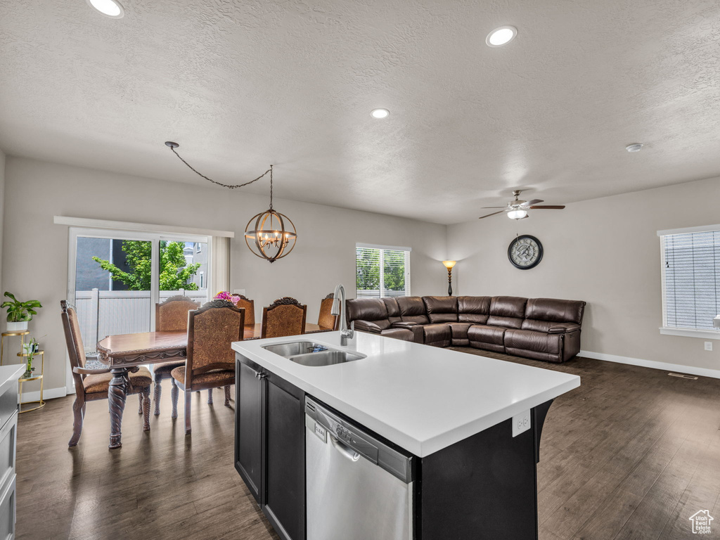 Kitchen featuring dishwasher, a sink, light countertops, dark wood-type flooring, and a textured ceiling