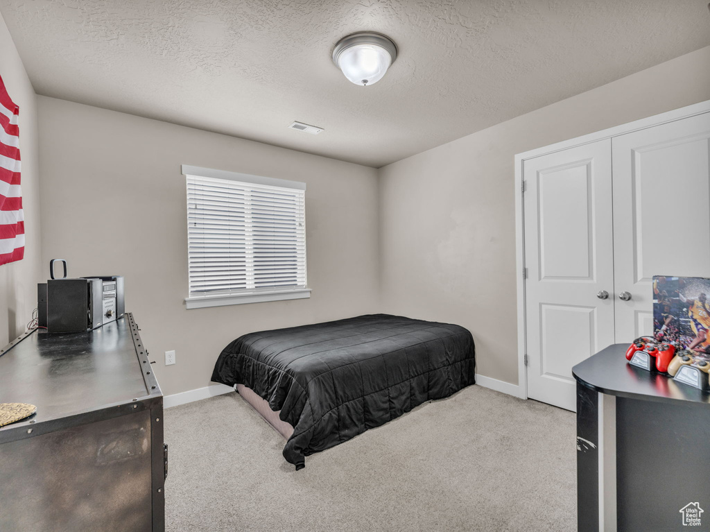Bedroom with carpet floors, baseboards, a textured ceiling, and a closet