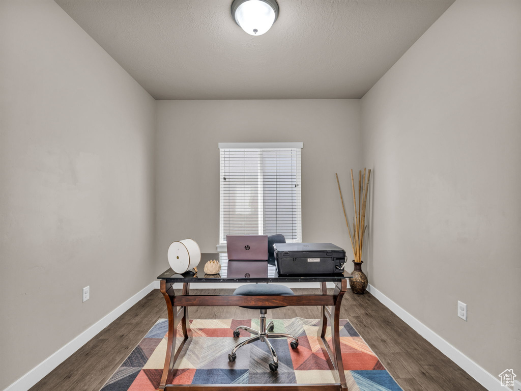 Office with dark wood-type flooring and baseboards