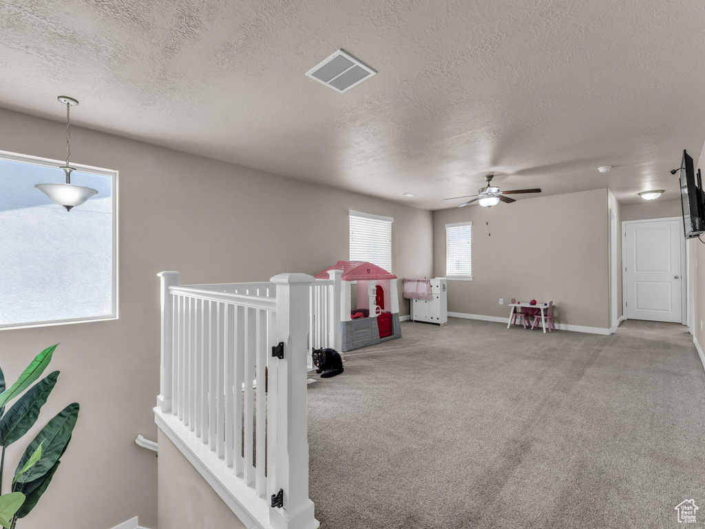 Recreation room featuring a textured ceiling, carpet, a ceiling fan, and baseboards