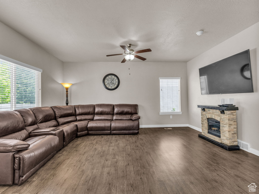 Living room with wood finished floors, a fireplace, ceiling fan, and baseboards