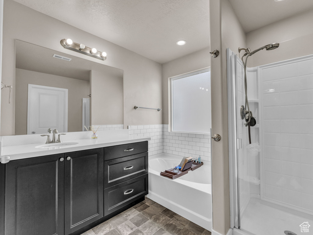 Full bath with a stall shower, a garden tub, and vanity