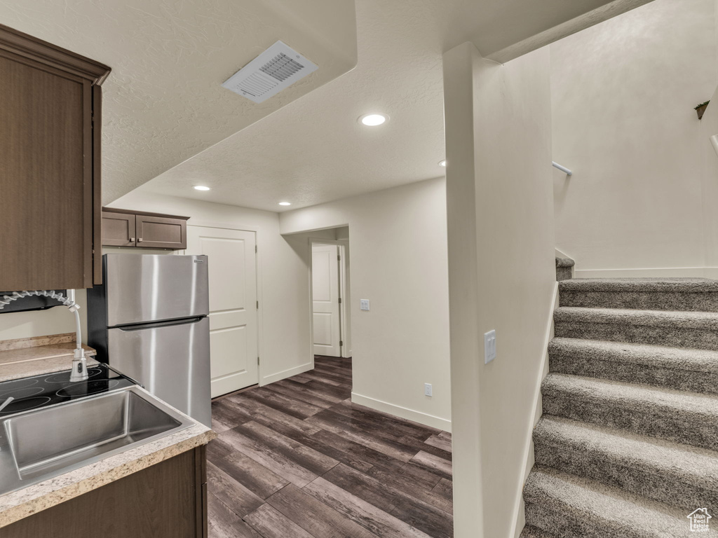 Kitchen featuring freestanding refrigerator, dark wood-style floors, recessed lighting, a sink, and dark brown cabinetry