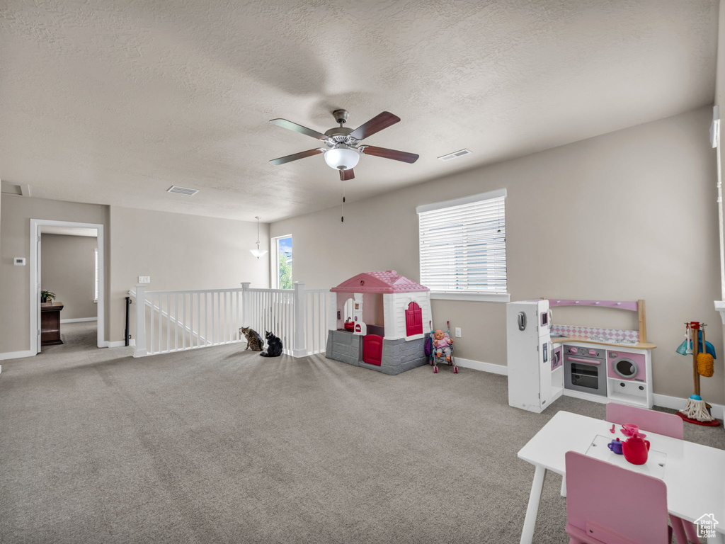 Playroom featuring ceiling fan, a textured ceiling, baseboards, and carpet flooring