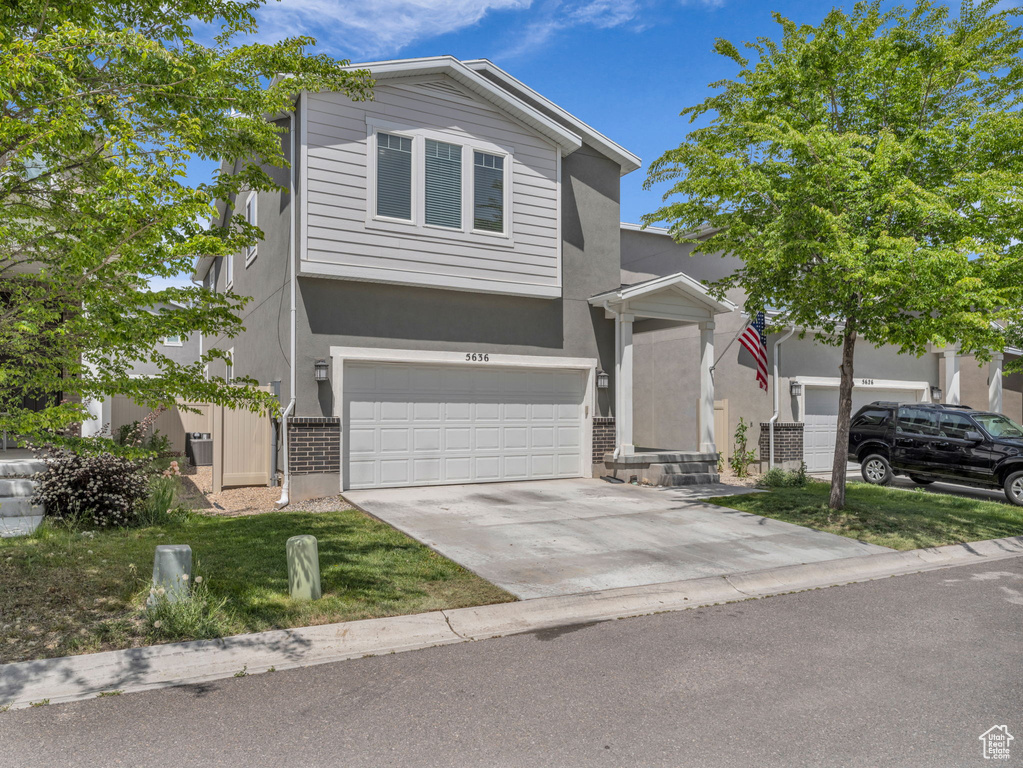 View of front of house featuring brick siding, stucco siding, driveway, and an attached garage