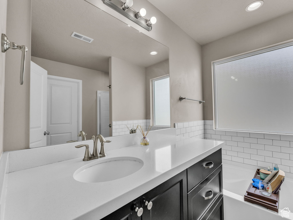 Full bathroom featuring vanity, a garden tub, and recessed lighting