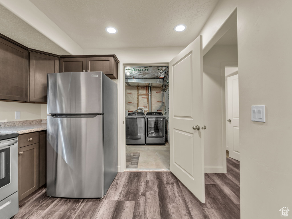 Kitchen featuring freestanding refrigerator, washer and clothes dryer, dark brown cabinetry, range, and recessed lighting