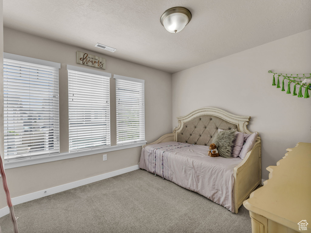 Carpeted bedroom with baseboards and a textured ceiling