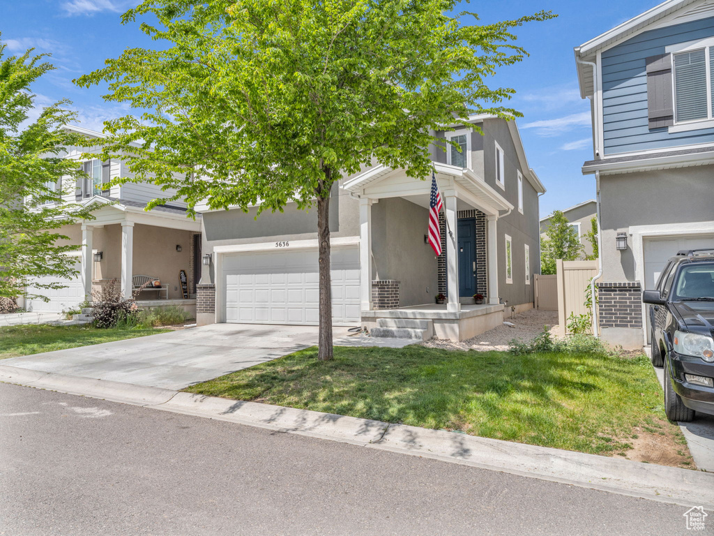 View of front of home with a garage, concrete driveway, and stucco siding