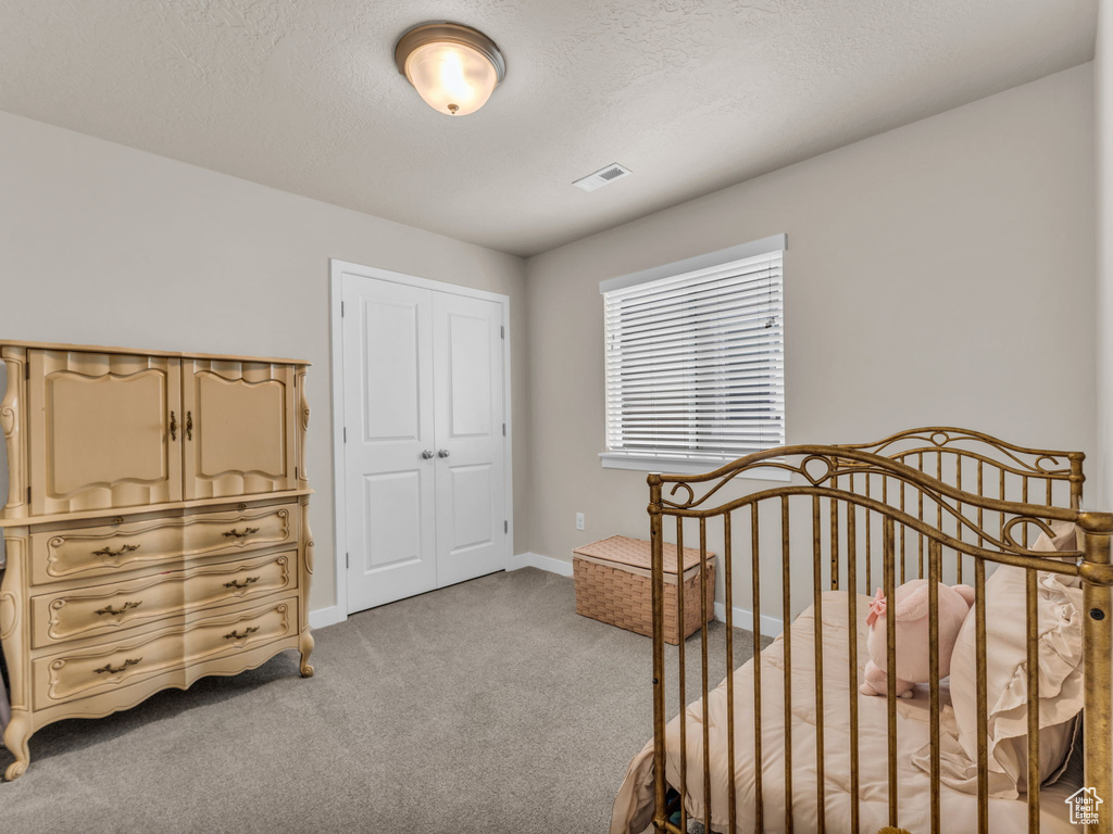 Bedroom with light colored carpet, baseboards, a closet, and a textured ceiling