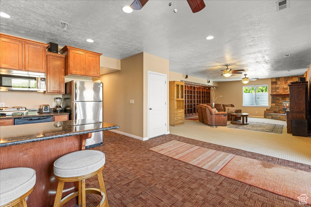 Kitchen featuring stainless steel appliances, a ceiling fan, carpet, a textured ceiling, and recessed lighting