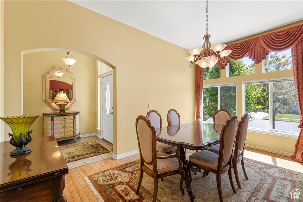 Dining room featuring arched walkways, light wood-type flooring, plenty of natural light, and a chandelier