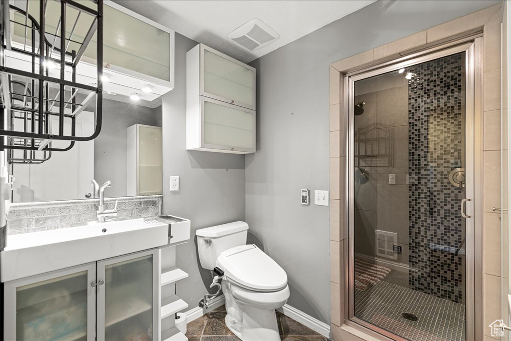 Bathroom with a stall shower, toilet, vanity, and baseboards