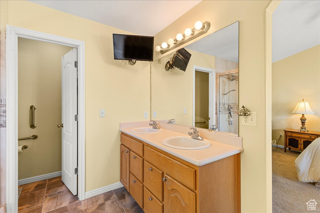 Full bathroom with double vanity, ensuite bath, baseboards, and a shower with door