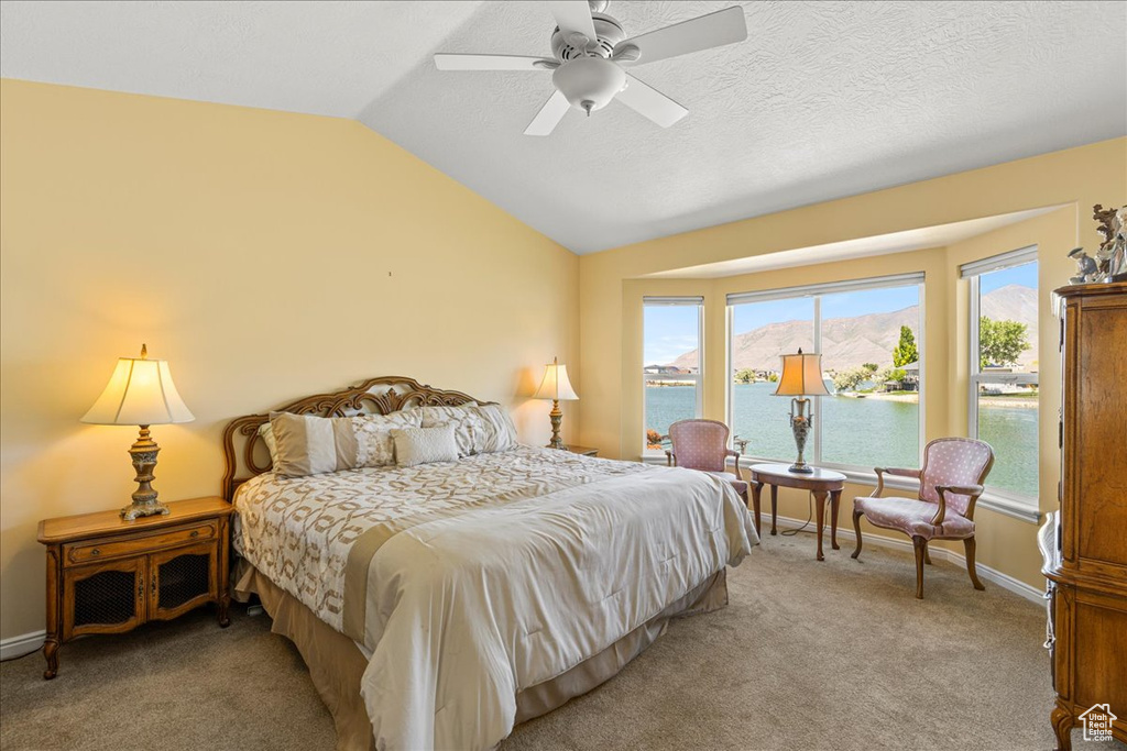 Bedroom with vaulted ceiling, multiple windows, a water view, light colored carpet, and ceiling fan