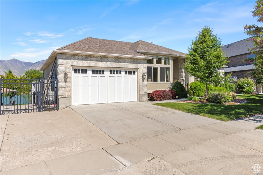 View of front of home featuring a garage, concrete driveway, a mountain view, and stone siding