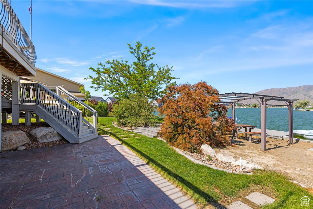 View of patio featuring a pergola, stairway, and a deck with water view