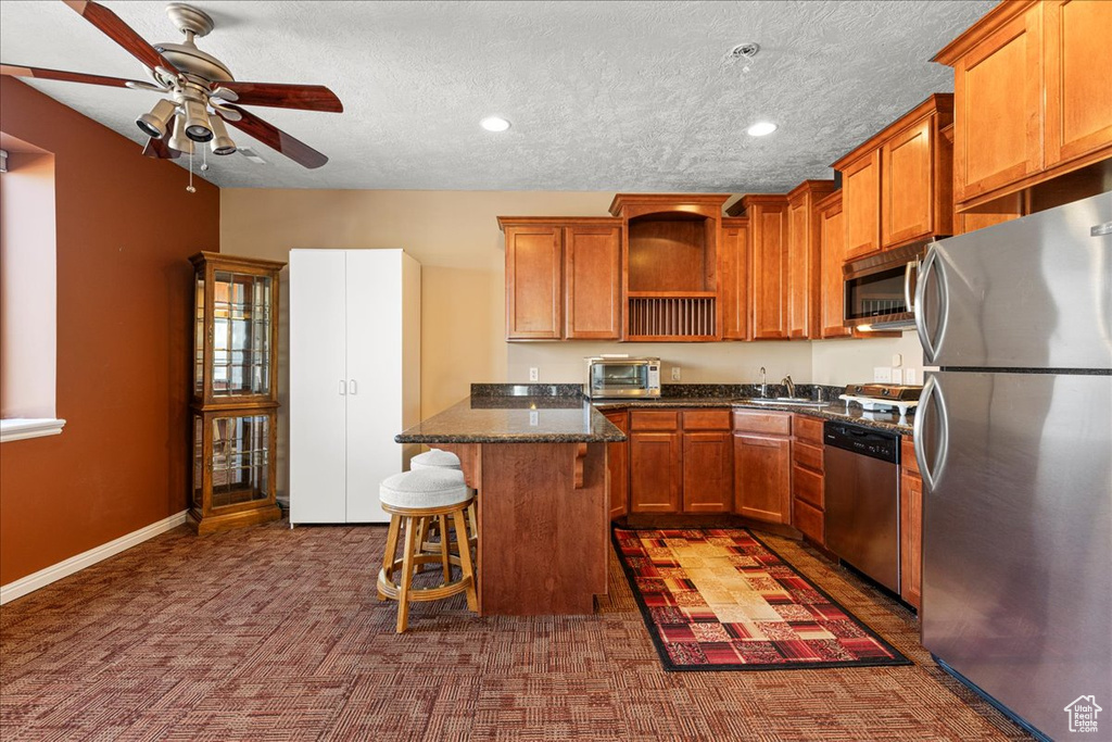 Kitchen featuring appliances with stainless steel finishes, open shelves, a kitchen breakfast bar, a ceiling fan, and a sink