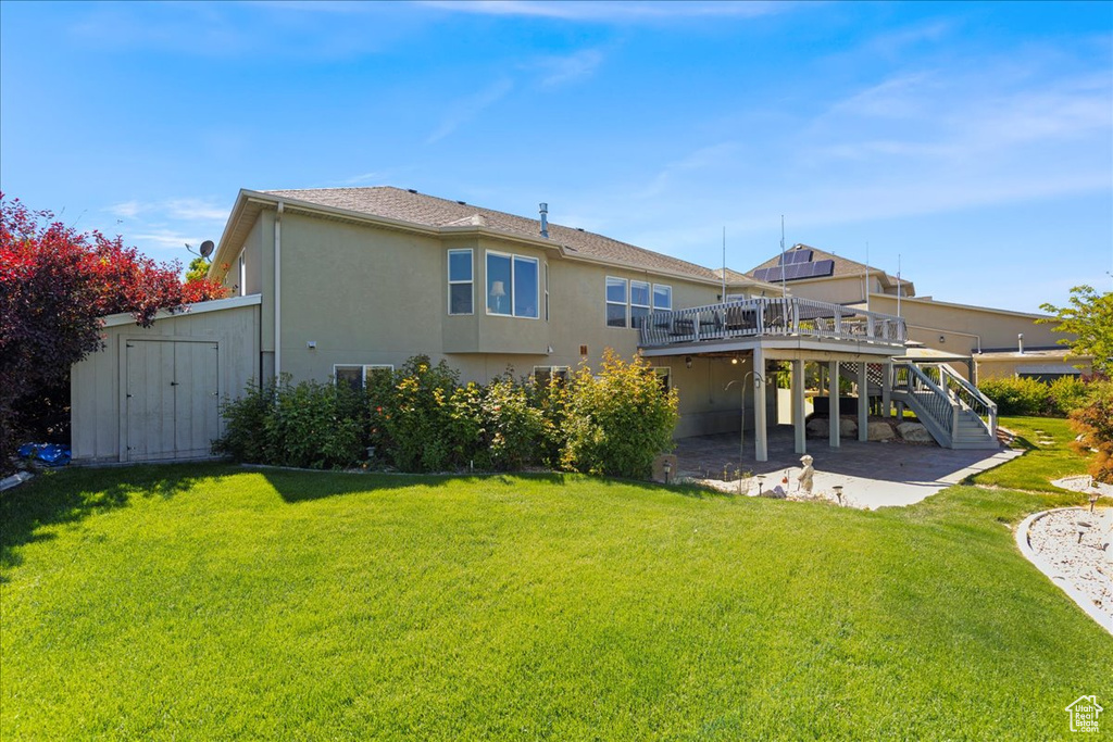 Back of property featuring a deck, stairs, stucco siding, a lawn, and a patio