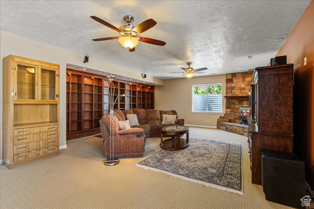 Living room with a textured ceiling, carpet flooring, a ceiling fan, and baseboards