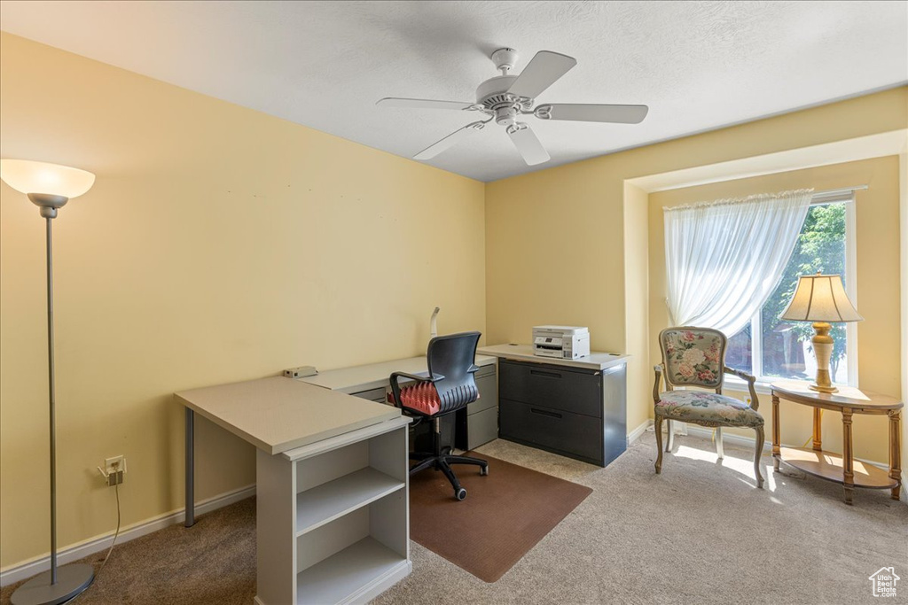 Carpeted home office with ceiling fan and baseboards